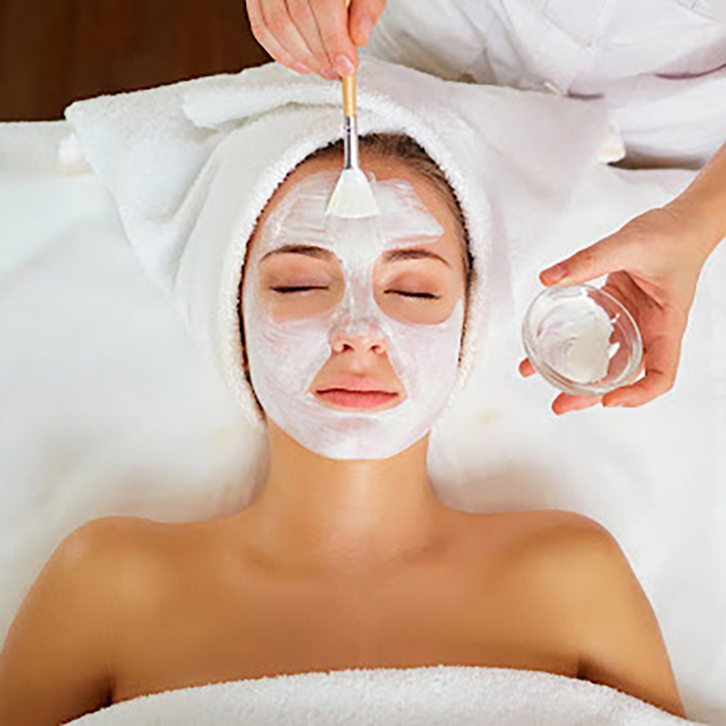 Woman with mask facial treatment on face in spa beauty salon.